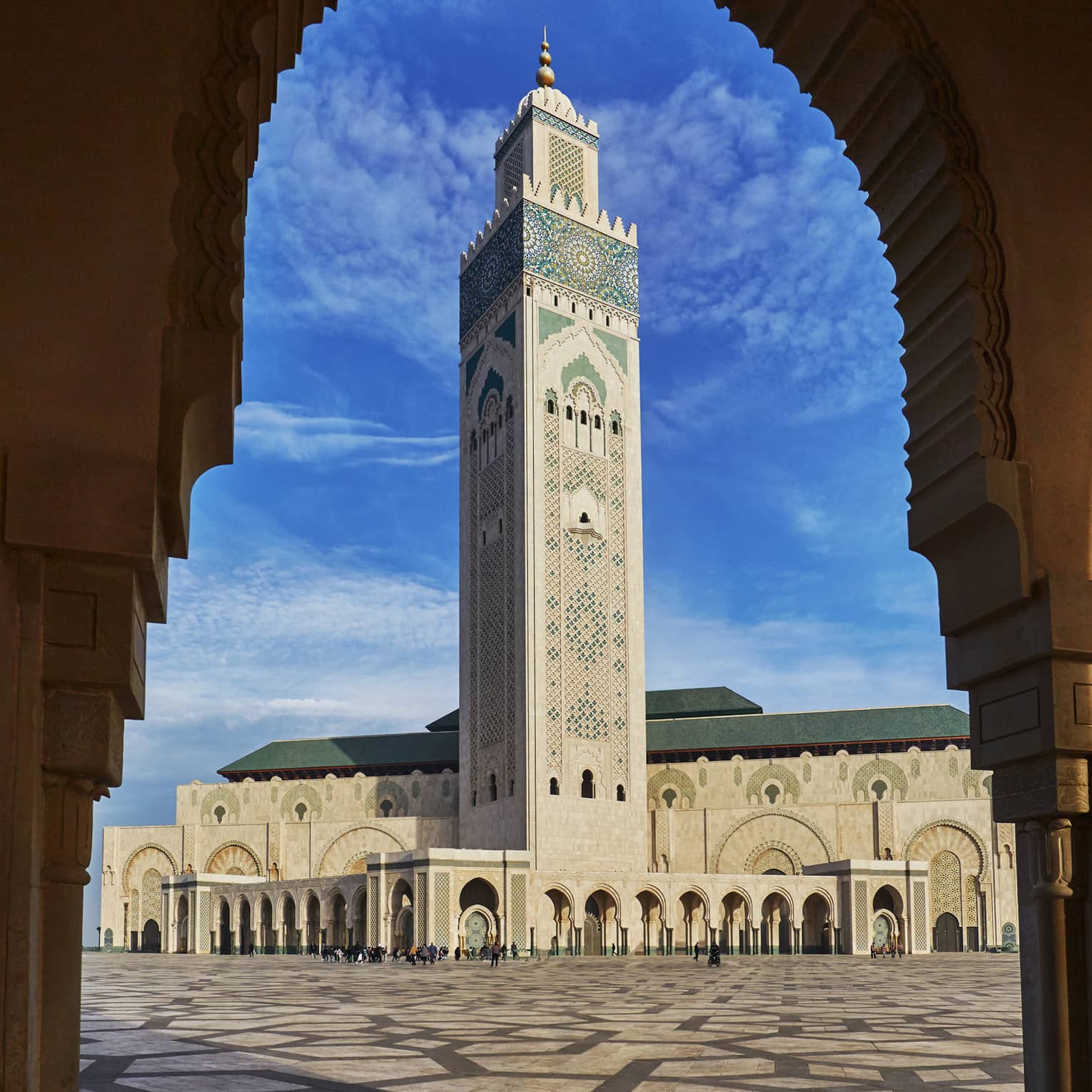 View from archway of Hassan II Mosque tall tower against blue sky 