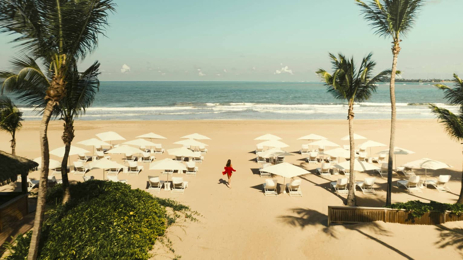 A white-sand beach with cluster of white lounge chairs and umbrellas