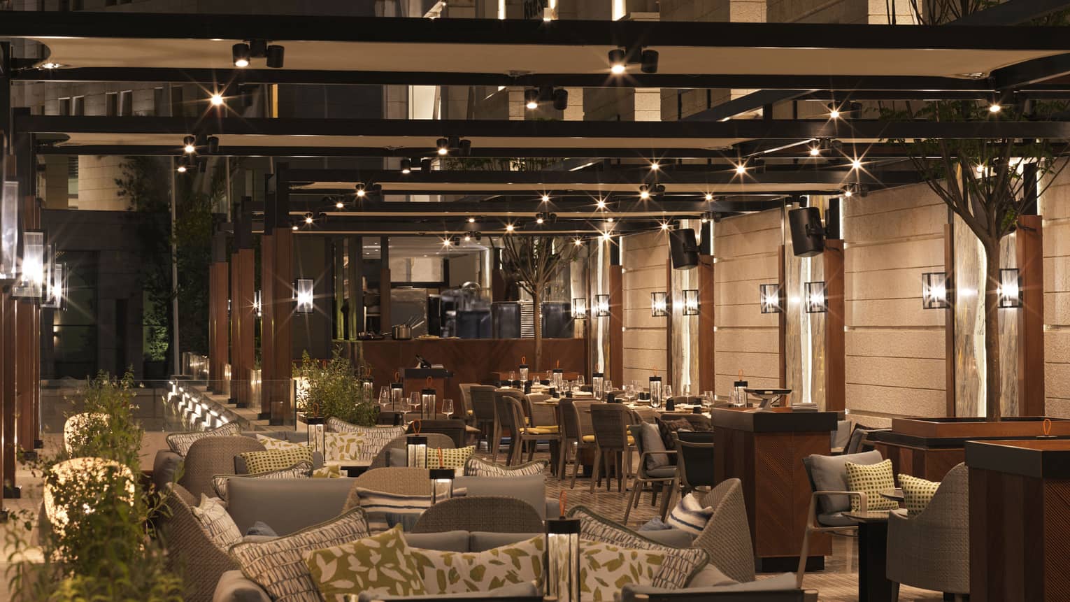 Two rows of tables and chairs fill a lantern-lit outdoor terrace