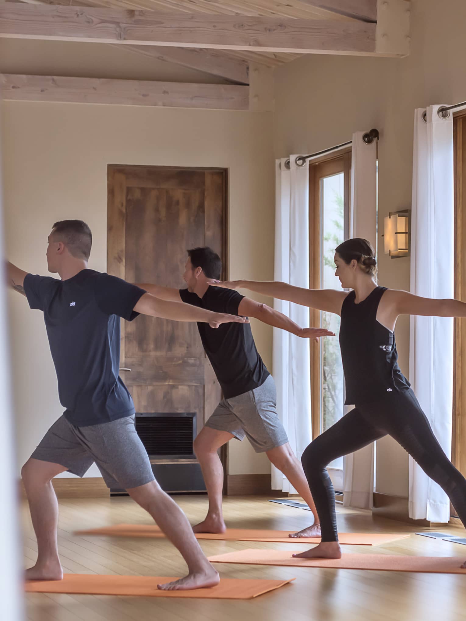 Three people perform yoga pose in Fitness Centre