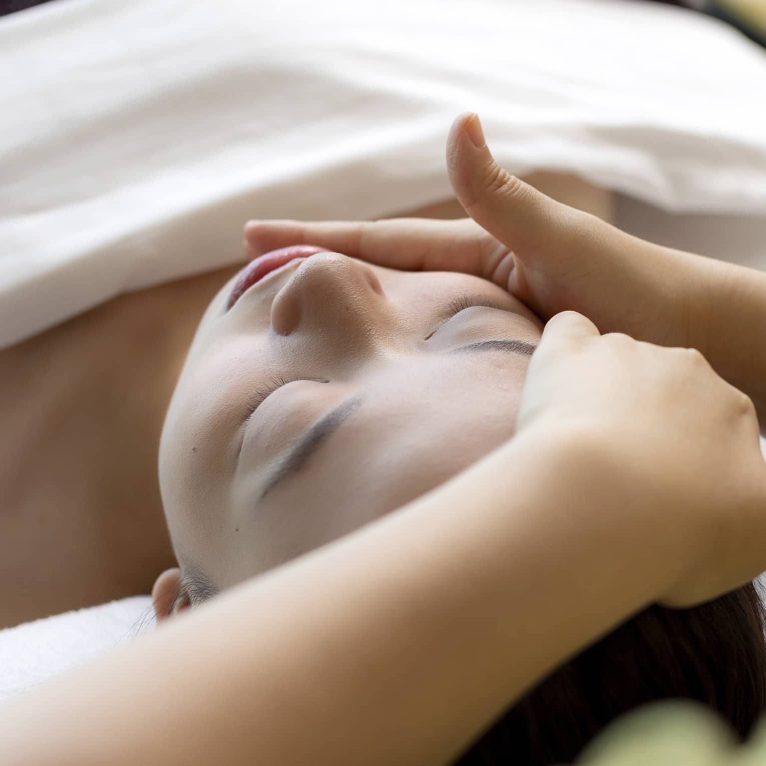 Hua Spa staff massages woman's face as she lays on treatment table