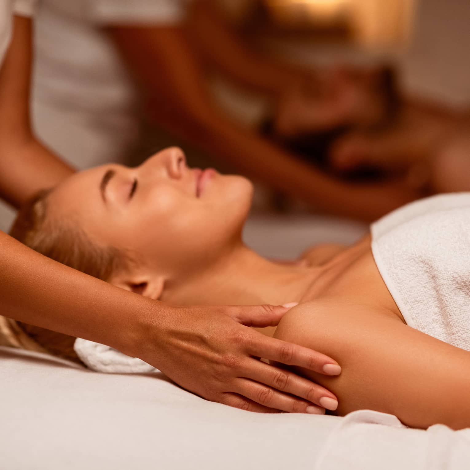 Two spa therapists perform a couples' massage