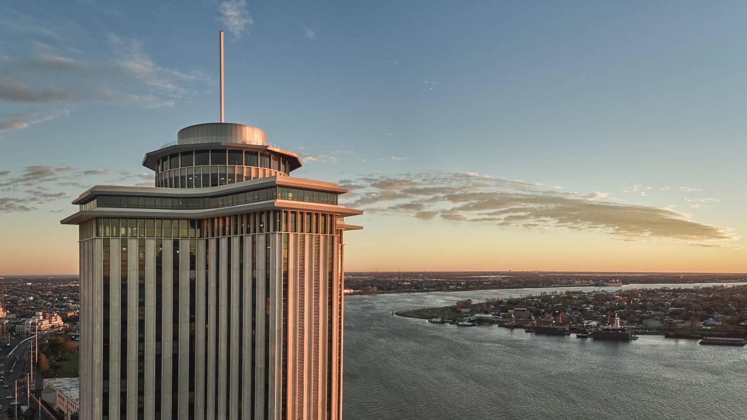 A tall building with water and a sunset behind it.