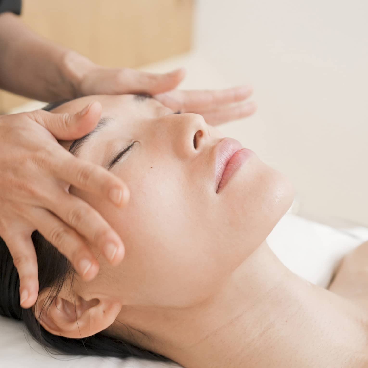 Person with eyes closed receiving head massage