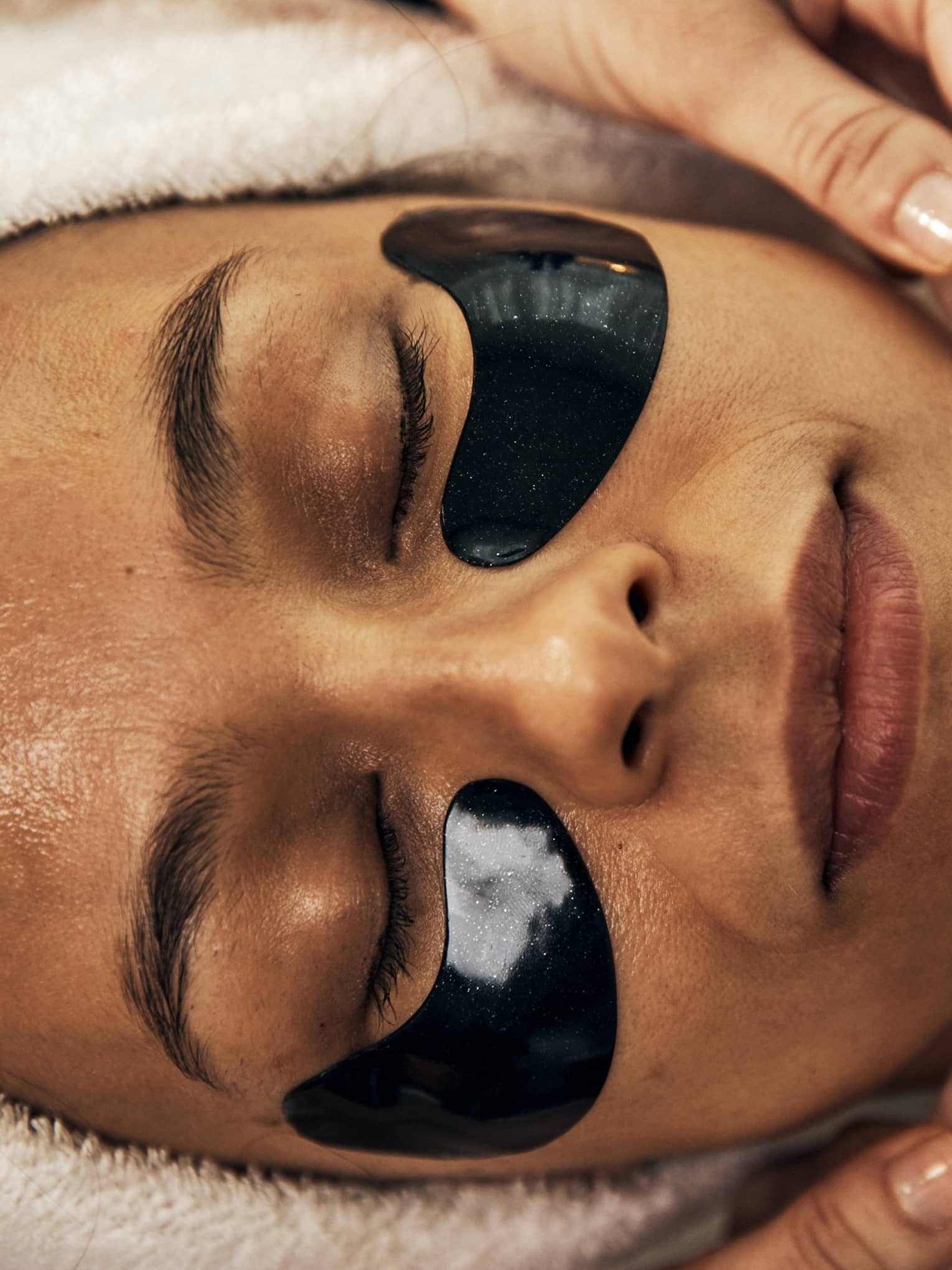 A woman getting a facial using crystals at a spa.