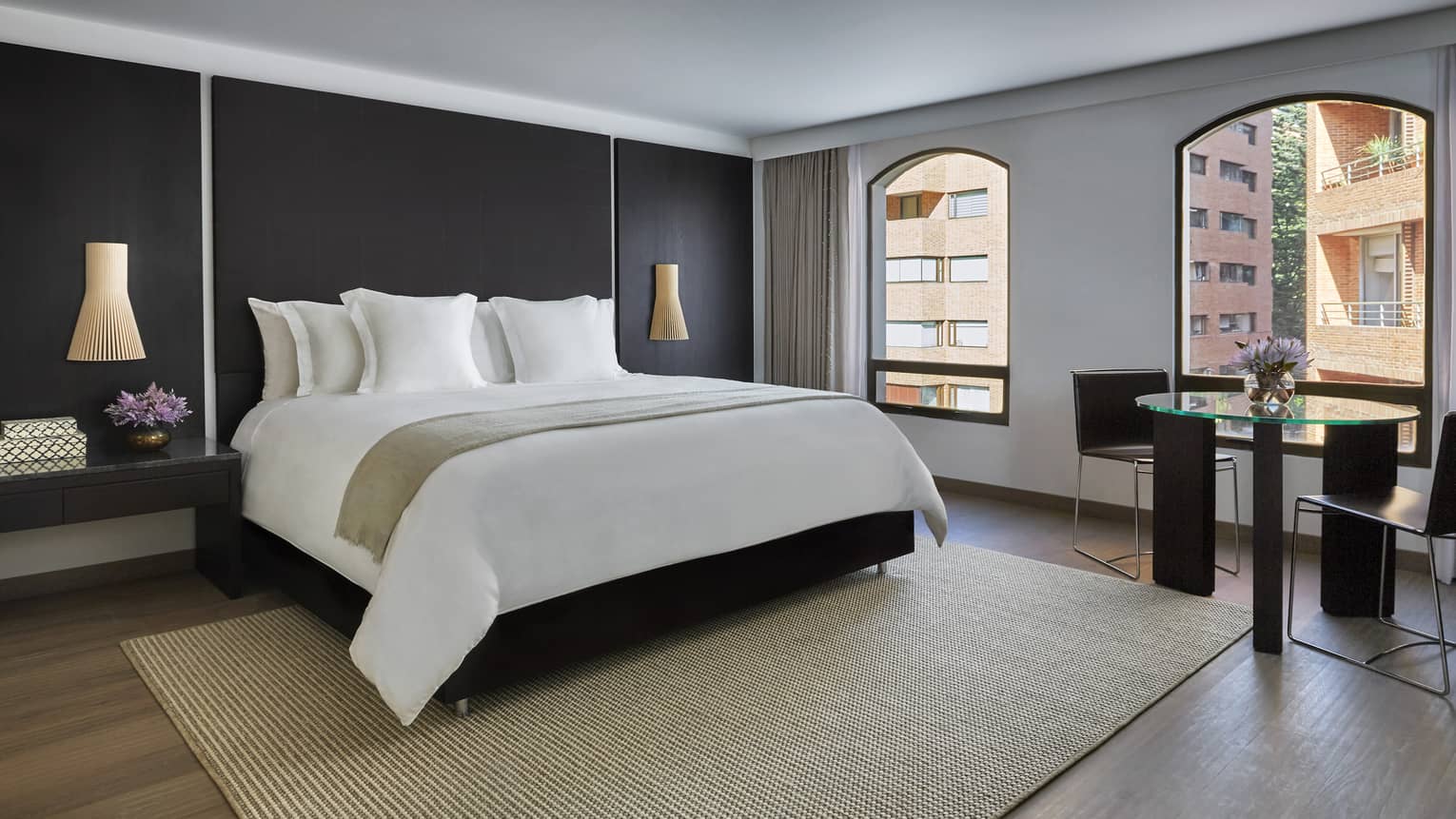 Grand Premier Room black wall, bed with white linens, bamboo rug, sunny windows with street views