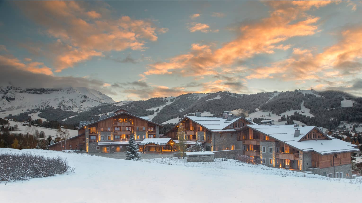 Four Seasons Hotel Megeve ski resort with lights at sunset on snowy mountain