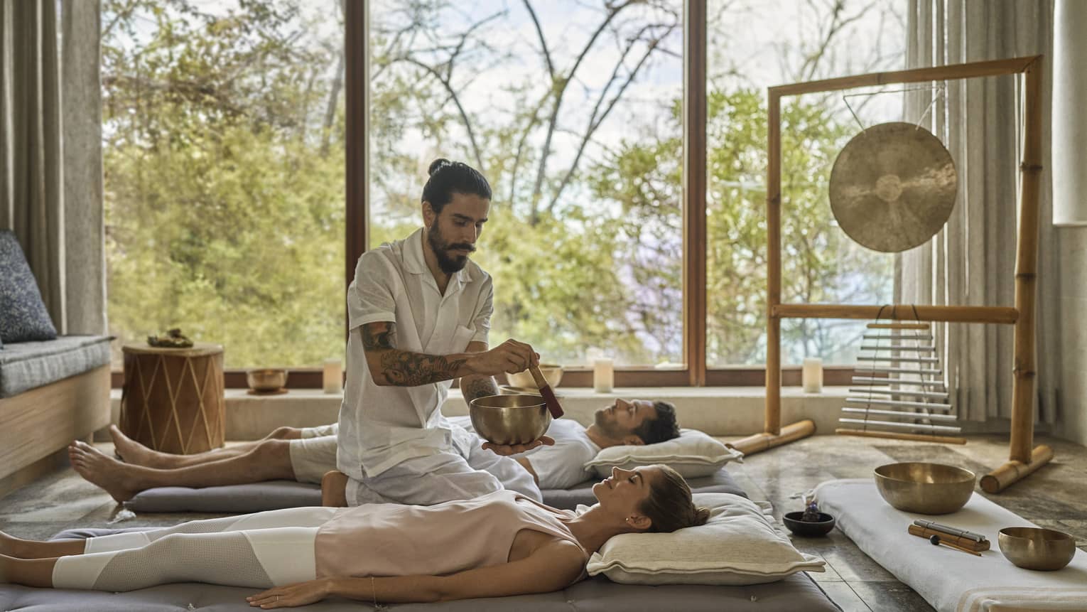 Two people on the floor in the Resort's Sound Room, as a man plays a Tibetan Singing Bowl next to them