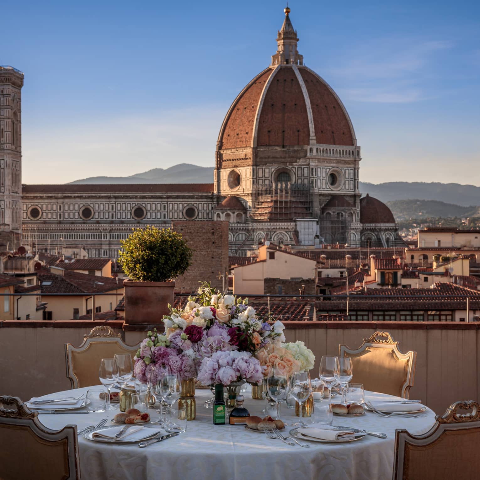 A white linen table set with flowers, and overlooking the historic downtown of Firenze. 