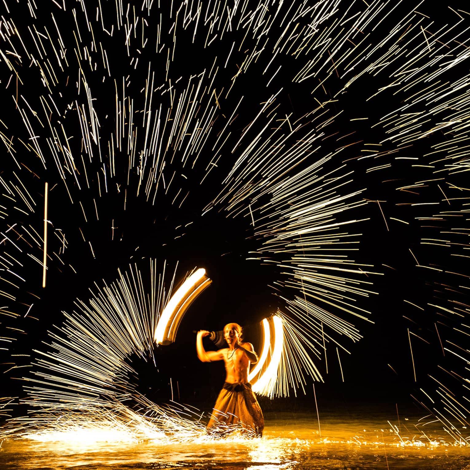 Streaks of light around man spinning fire 