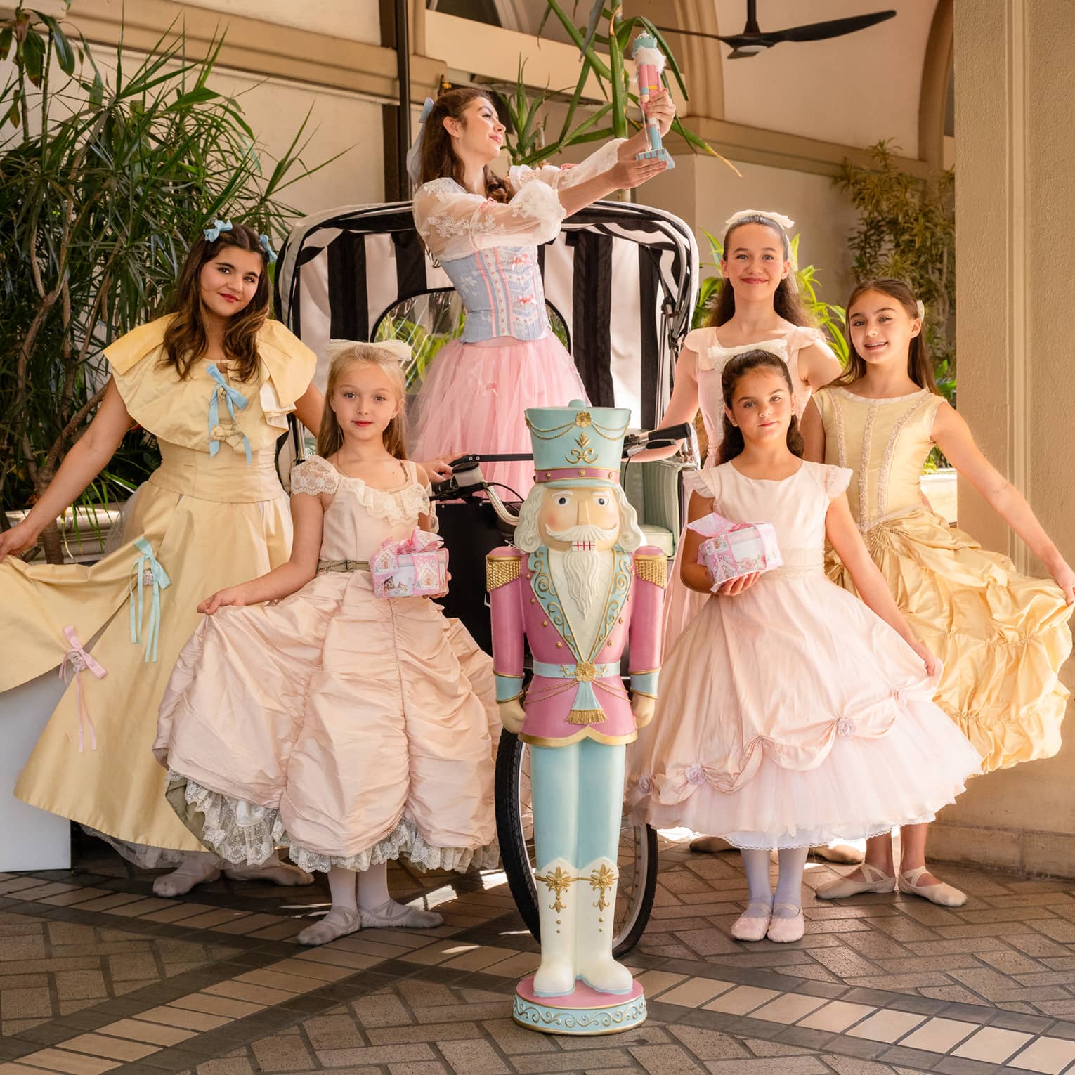 Ballet dancers pose around a pastel-coloured nutcracker
