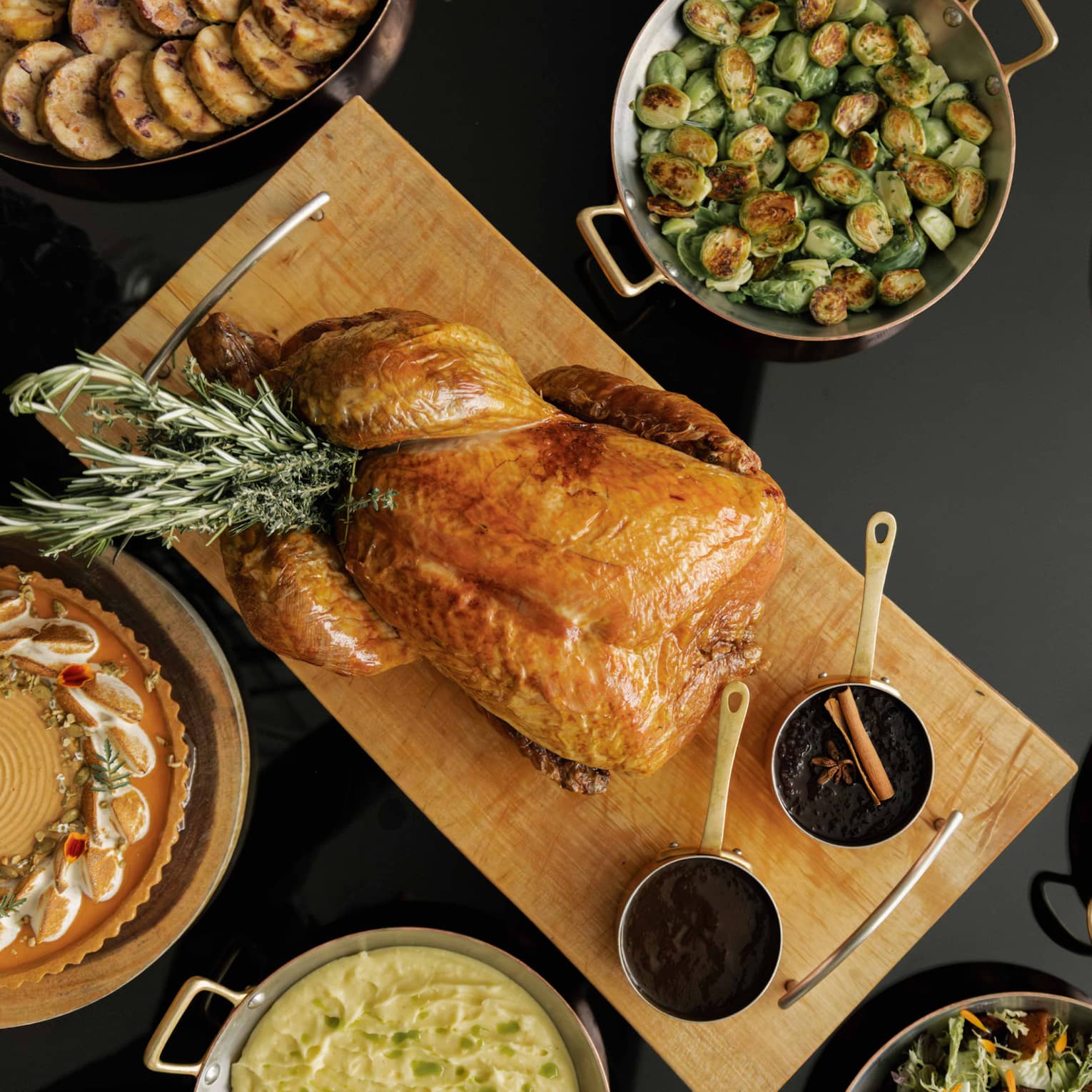 Table set with a roasted turkey, Brussels sprouts, sliced carrots and various other dishes for a holiday meal,Table set with a roasted turkey, Brussels sprouts, clived carrots and various other dishes for a holiday meal