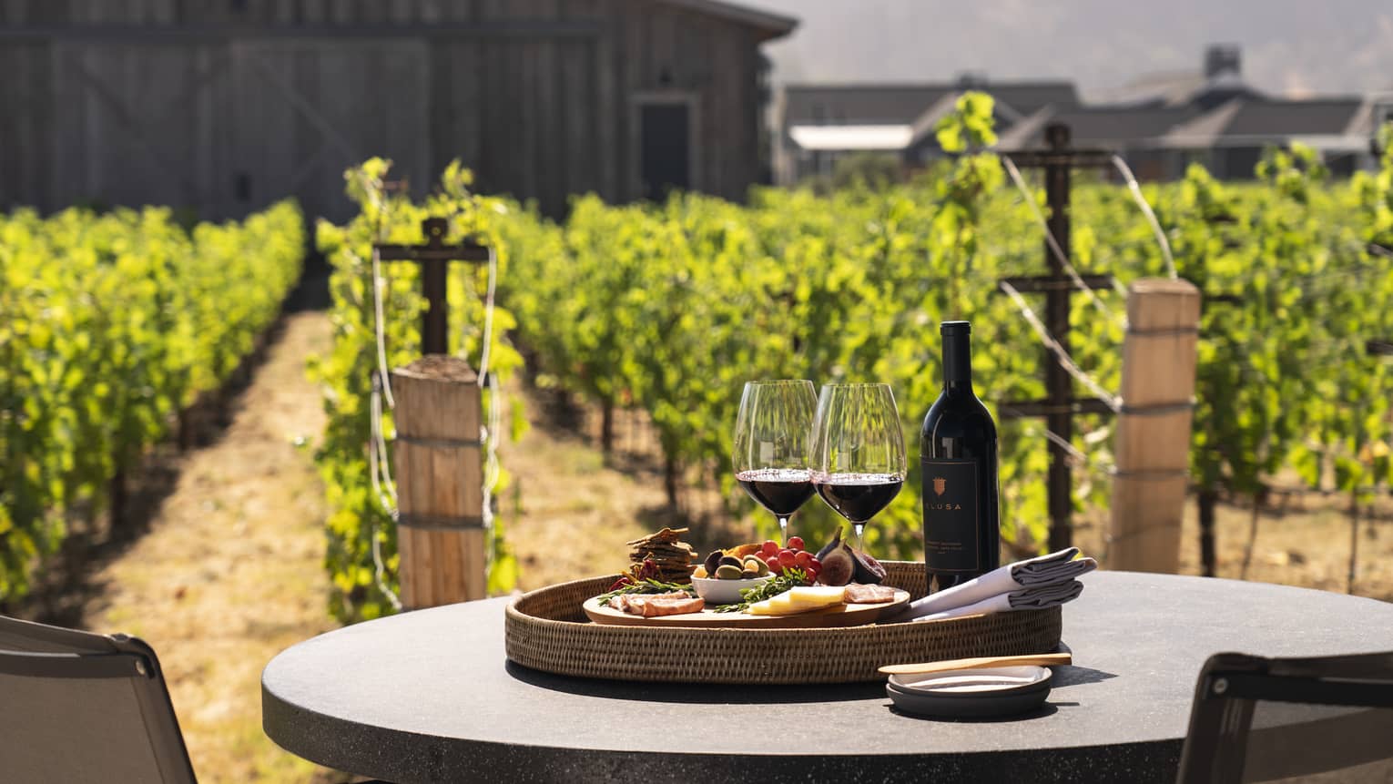 Two wine glasses with a plate of snacks on an outdoor dining table.
