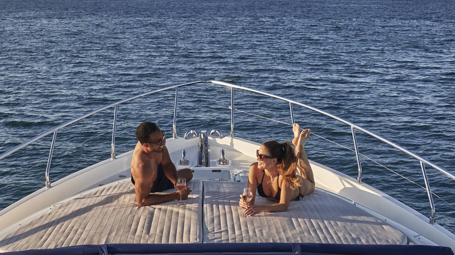 Man and woman lay on front of yacht