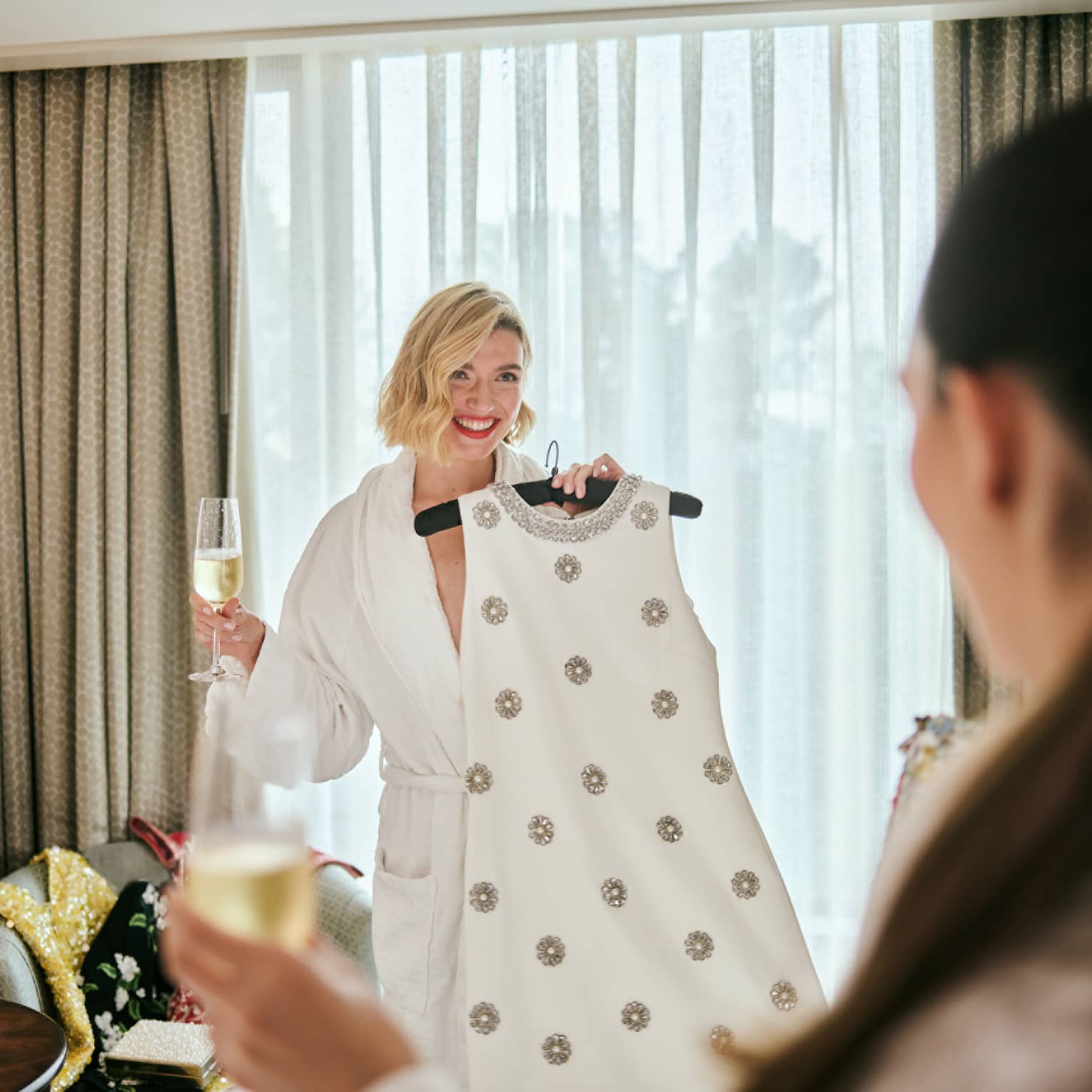 A person wearing a robe and holding a dress on a hanger