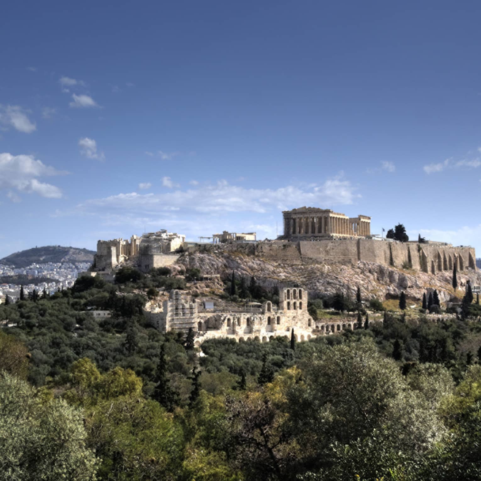 Ancient ruins of Acropolis on mountain surrounded by greenery 