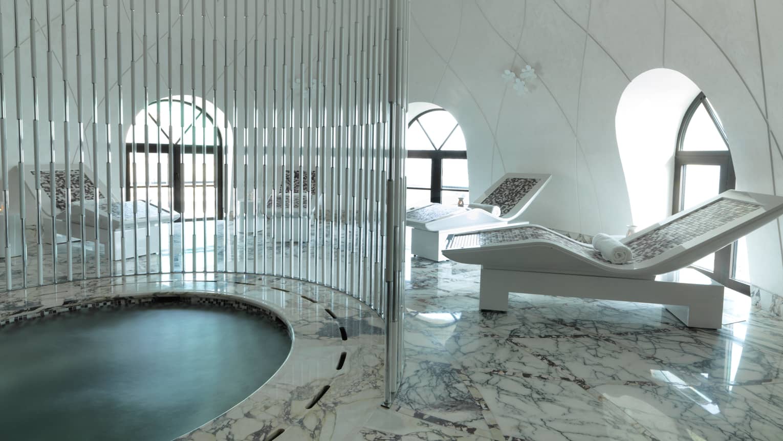 Round spa pool with metal rod divider, white lounge chairs on marble deck, white dome room