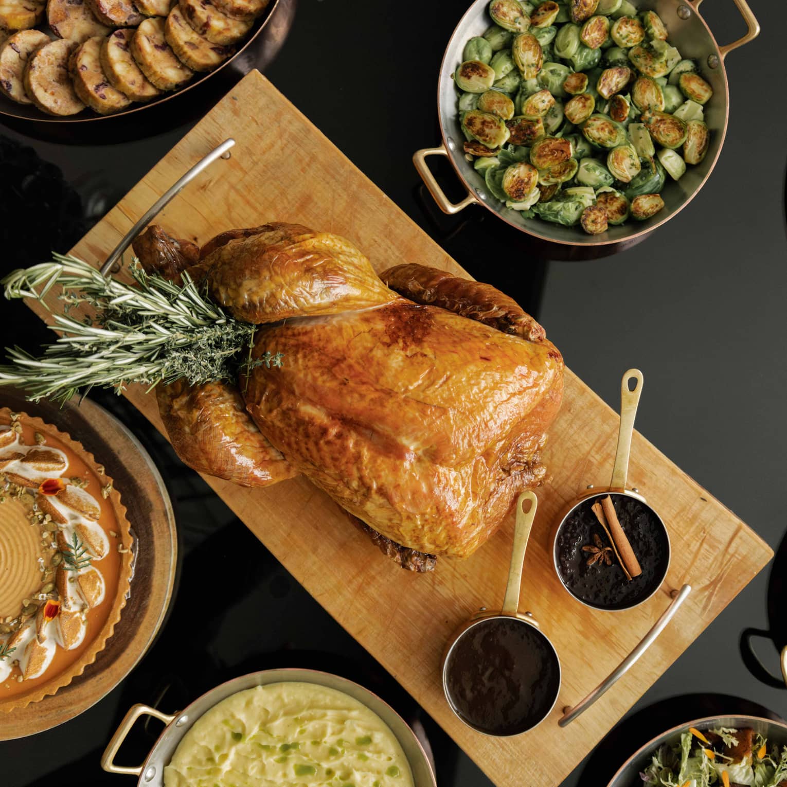 Table set with a roasted turkey, Brussels sprouts, sliced carrots and various other dishes for a holiday meal,Table set with a roasted turkey, Brussels sprouts, clived carrots and various other dishes for a holiday meal