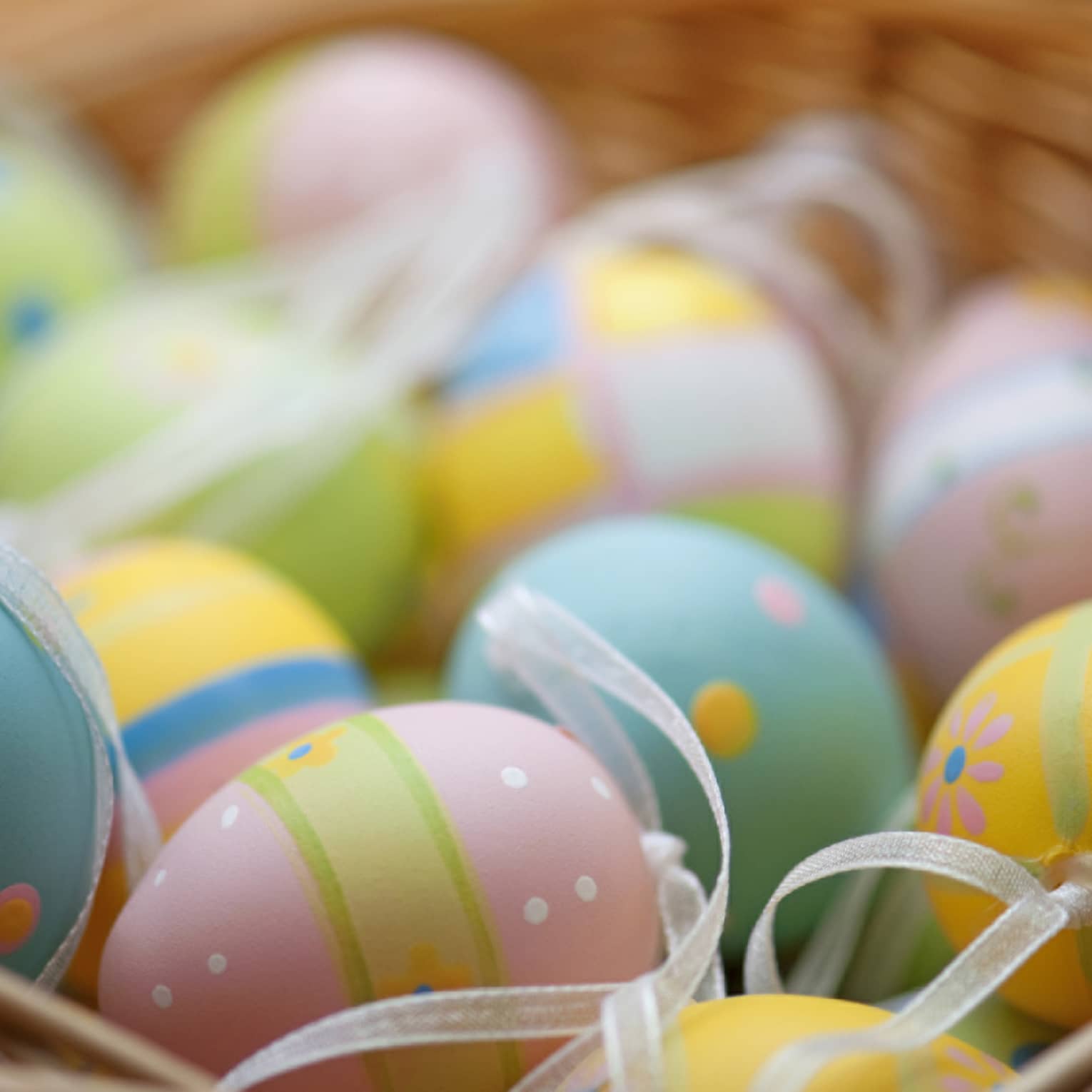 A basket of blue, pink, green and yellow colourful Easter eggs.
