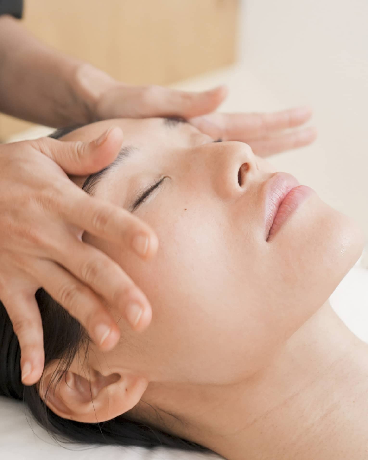 Person with eyes closed receiving head massage