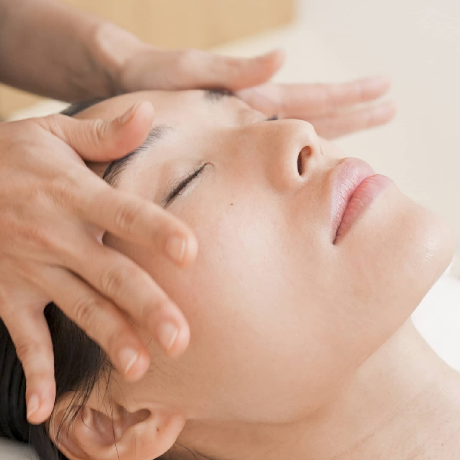 Person with eyes closed receiving head massage