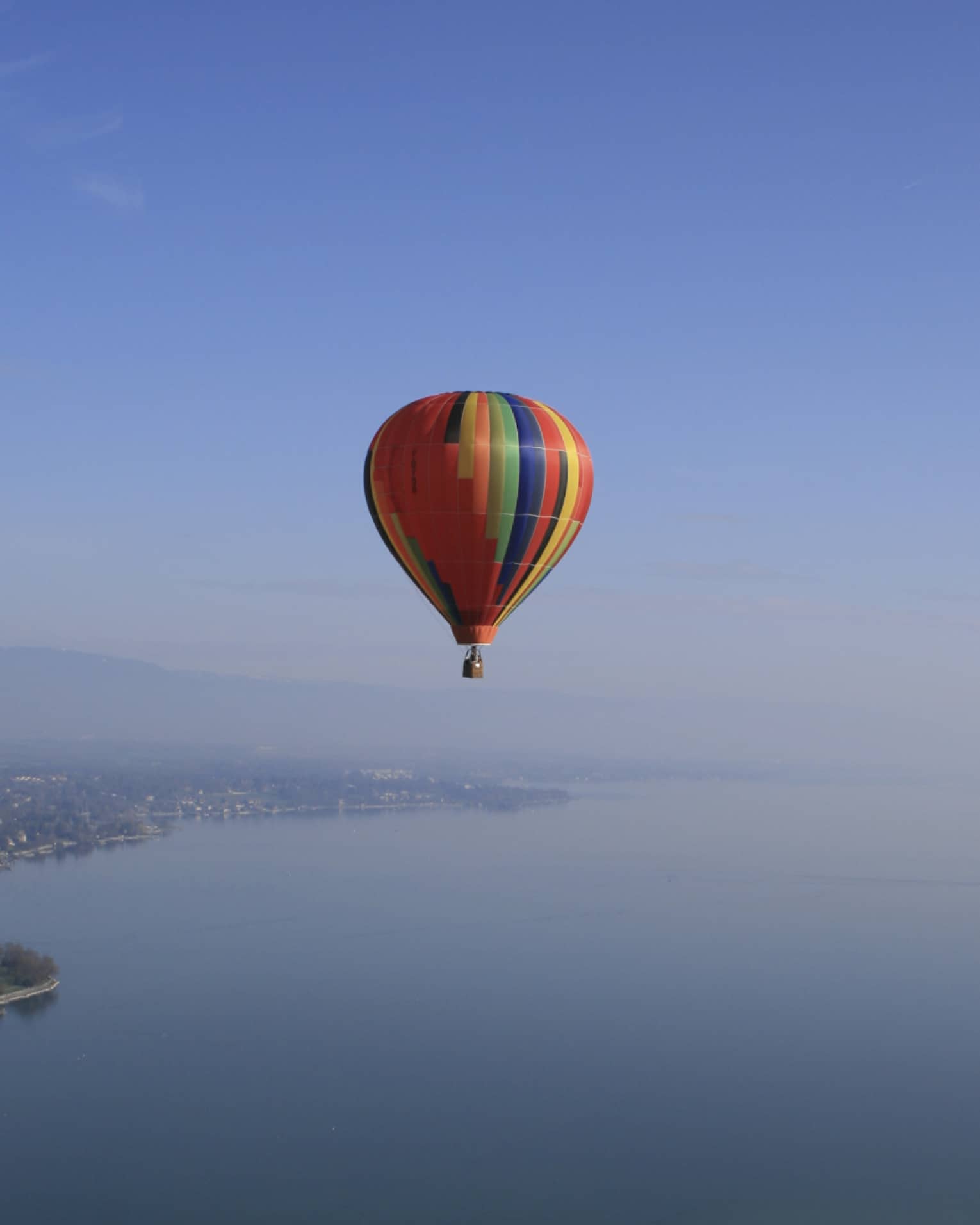 Colourful striped hot air balloon floating over Lake Geneva