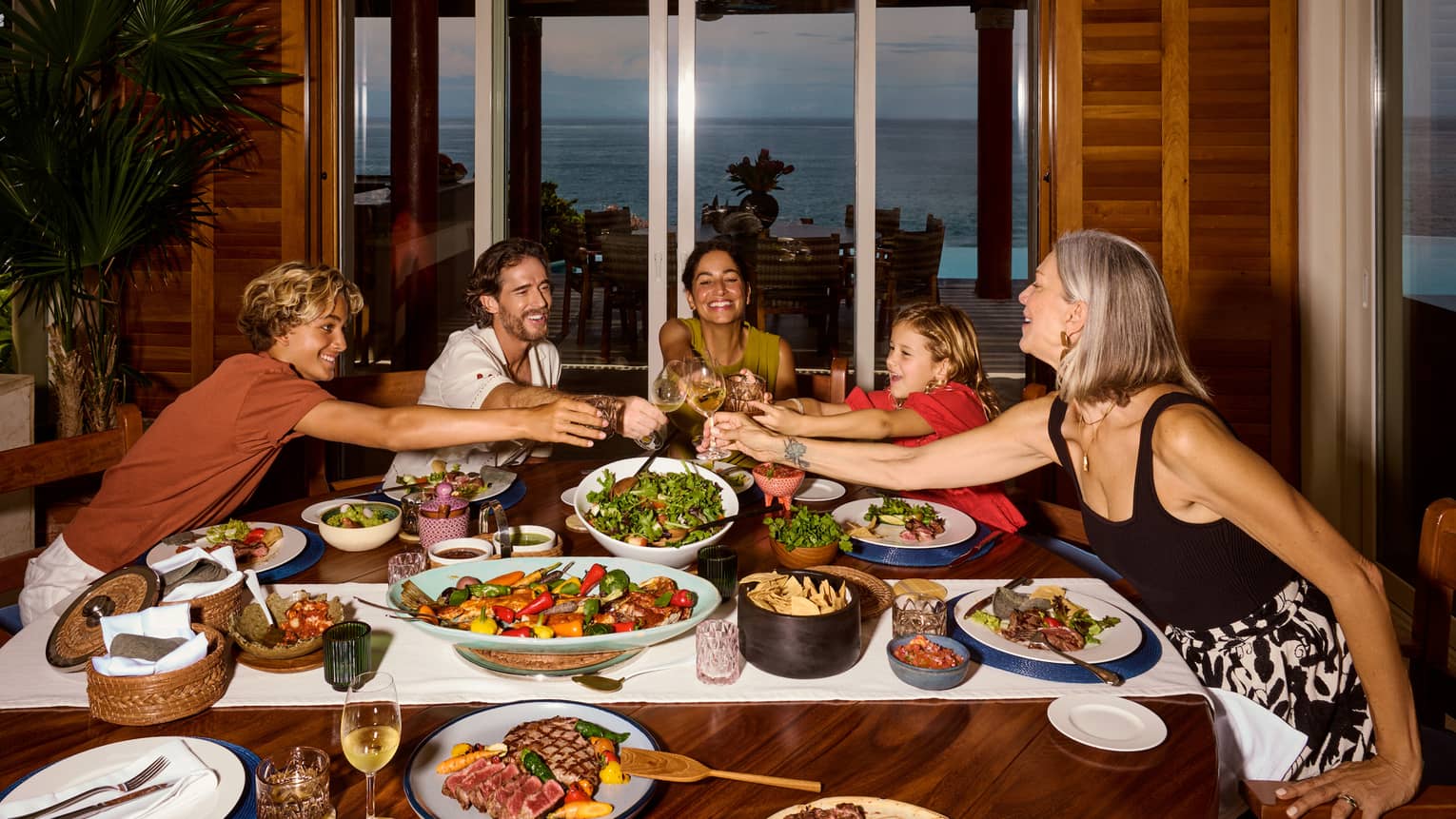 Family of five toasting at a table full of colourful dishes