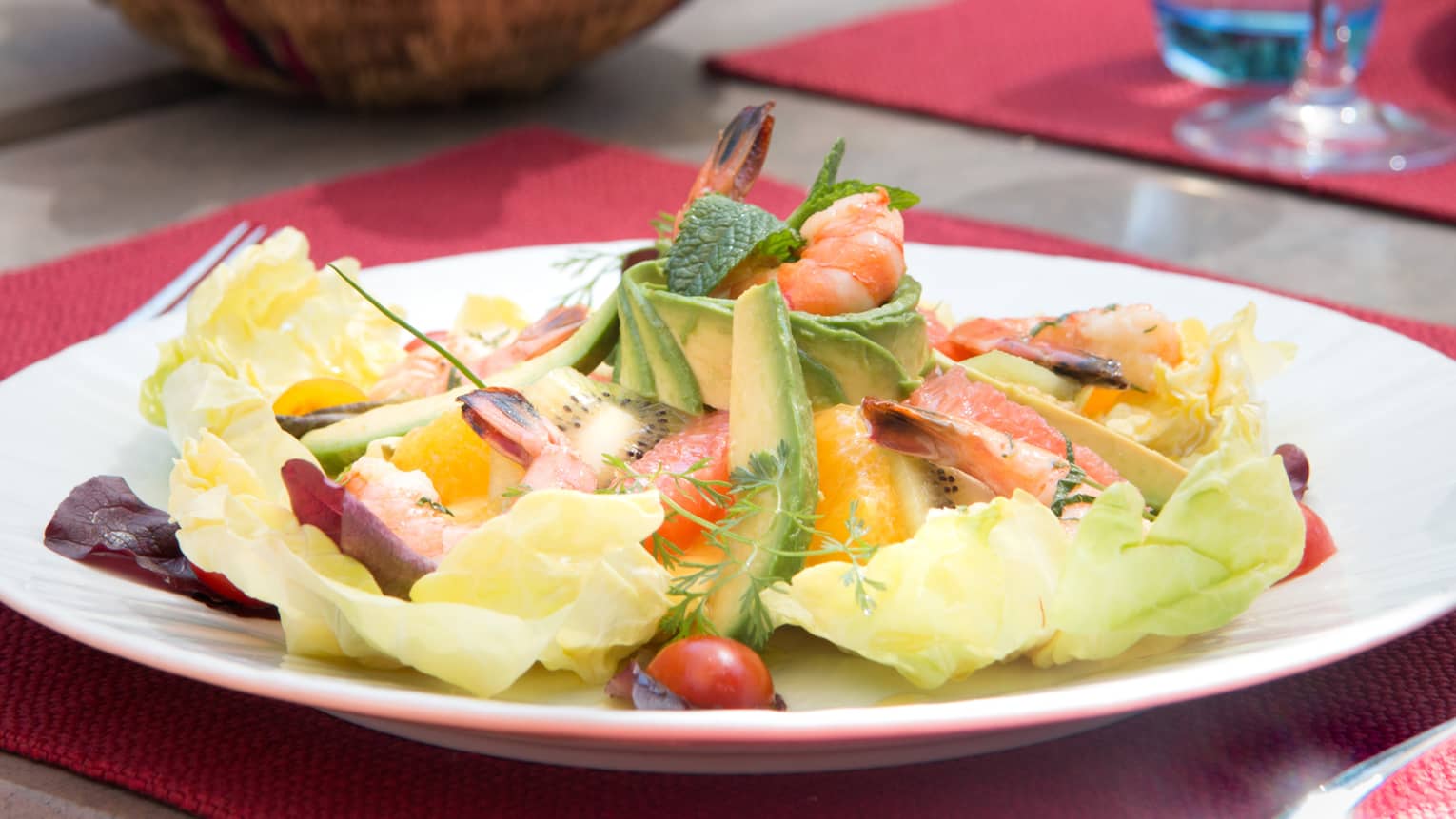 Cobb gambas salad with sliced avocado, egg, fruit arranged in layers on plate