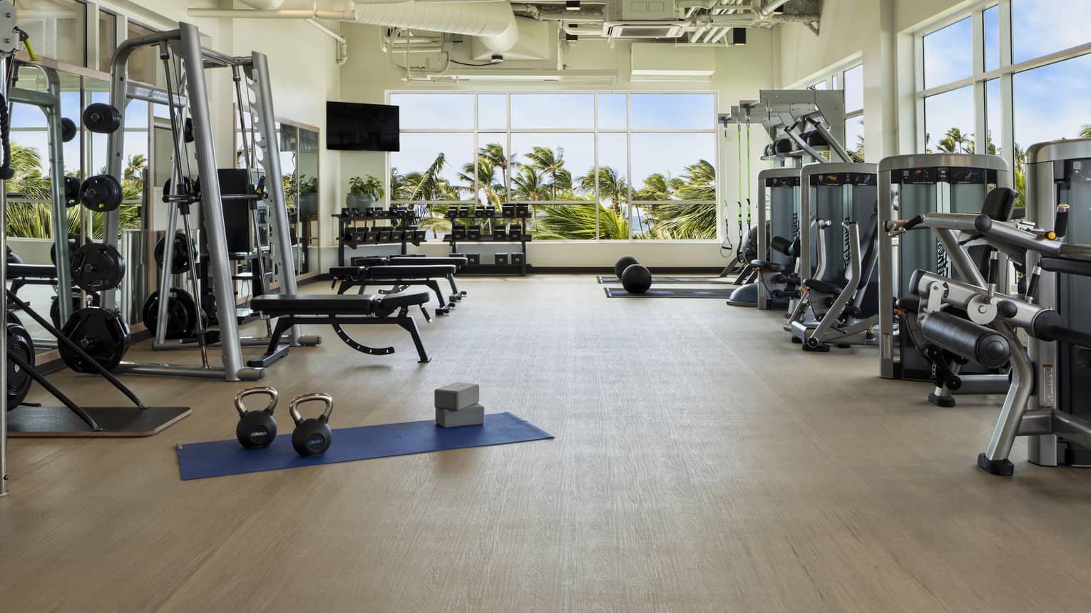 Large light-filled fitness centre with various weight training machines, free weights and cardio machines at Four Seasons Resort Oahu