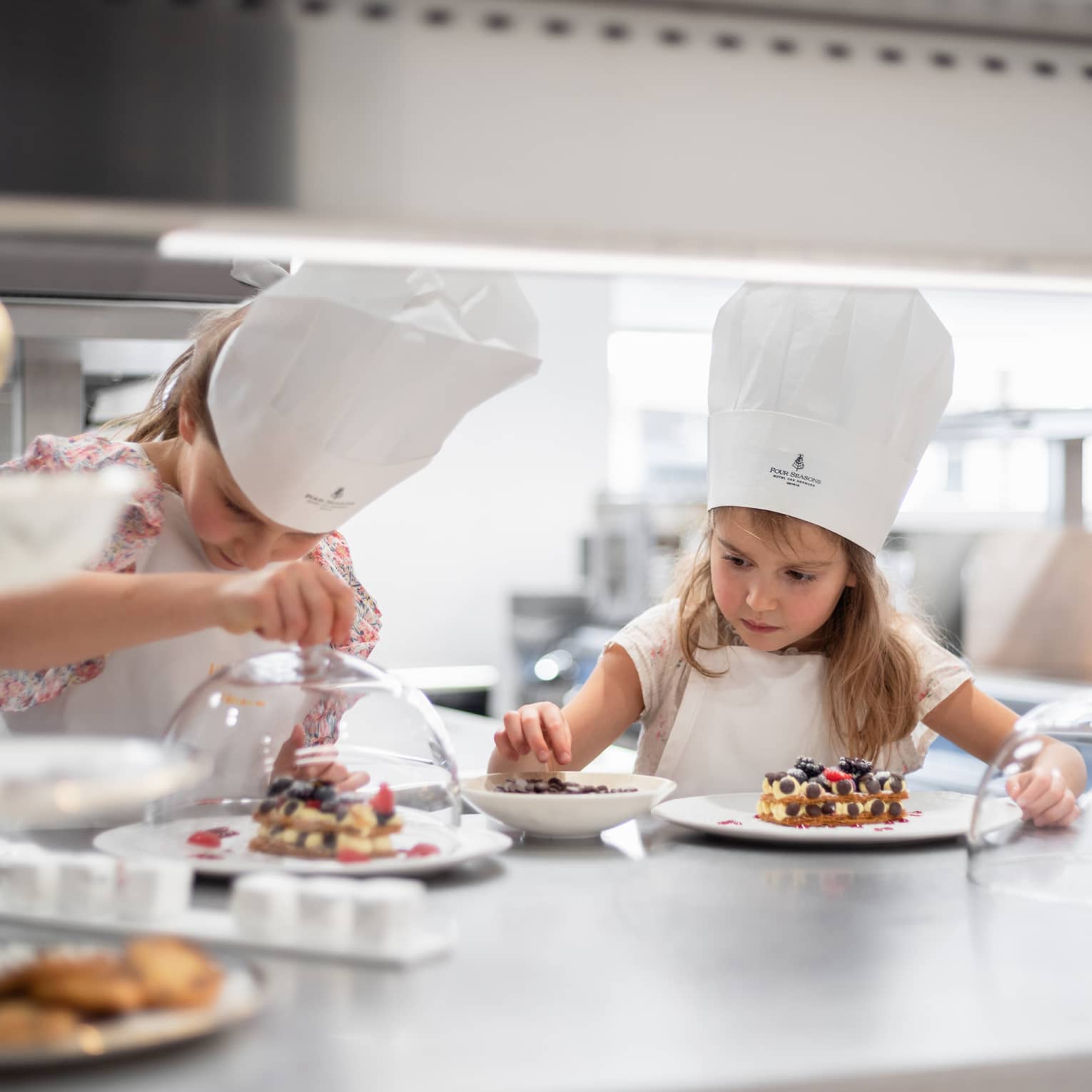 Two girls in chef hats making dessert in hotel kitchen