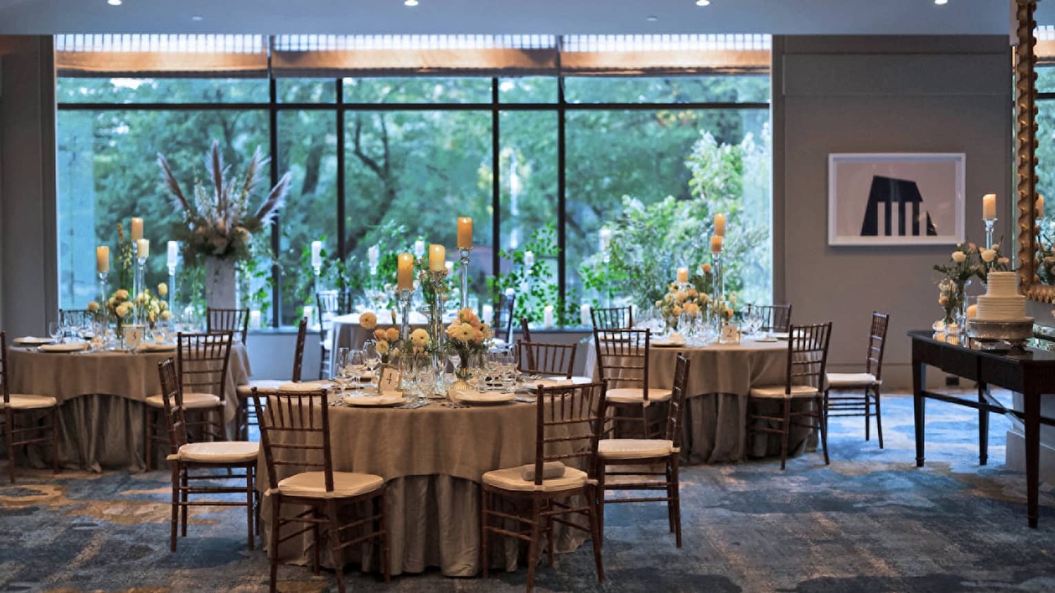 A room with dining tables and a large window on the back wall.