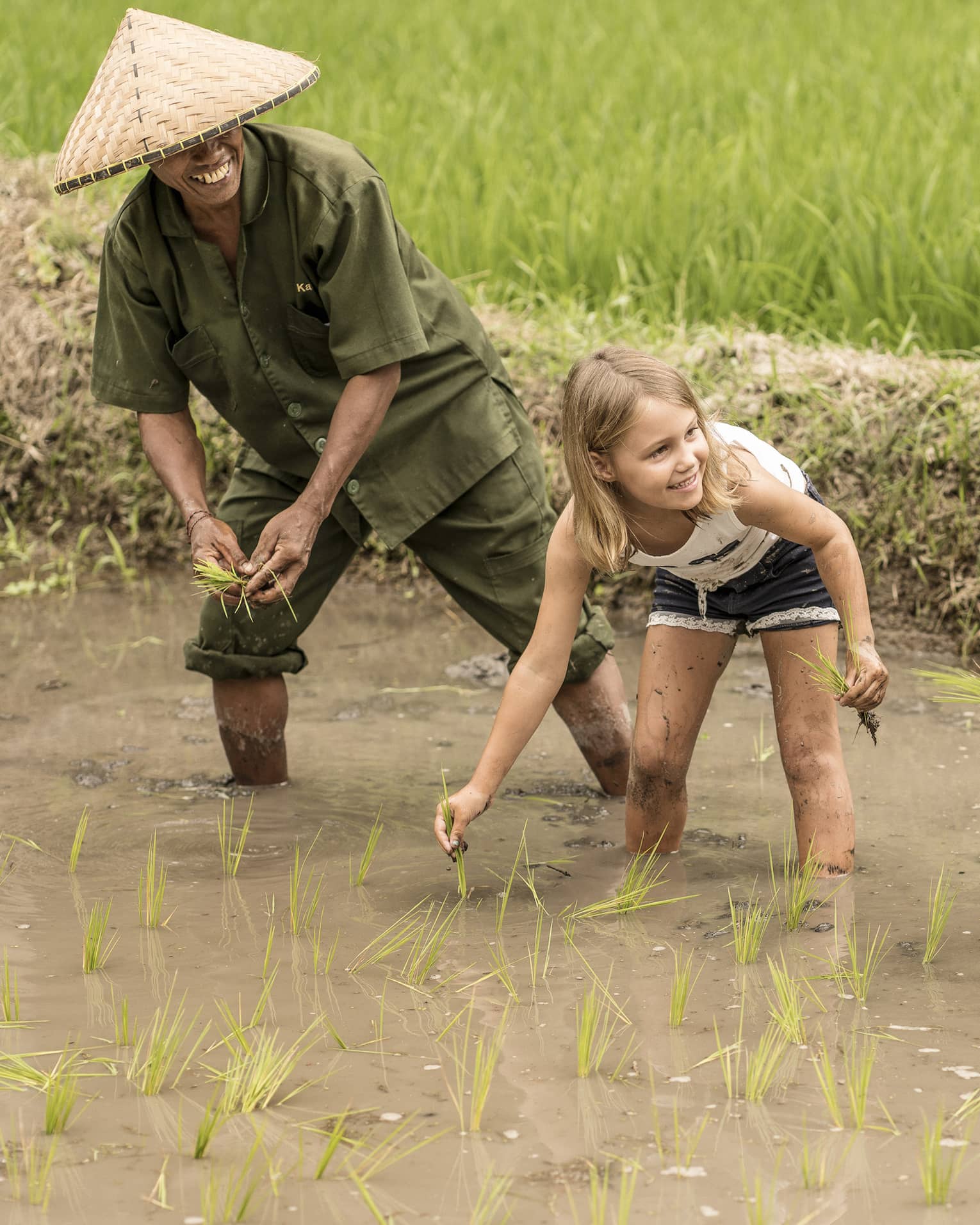 Four Seasons guests work in a rice field alongside a balinese farmer