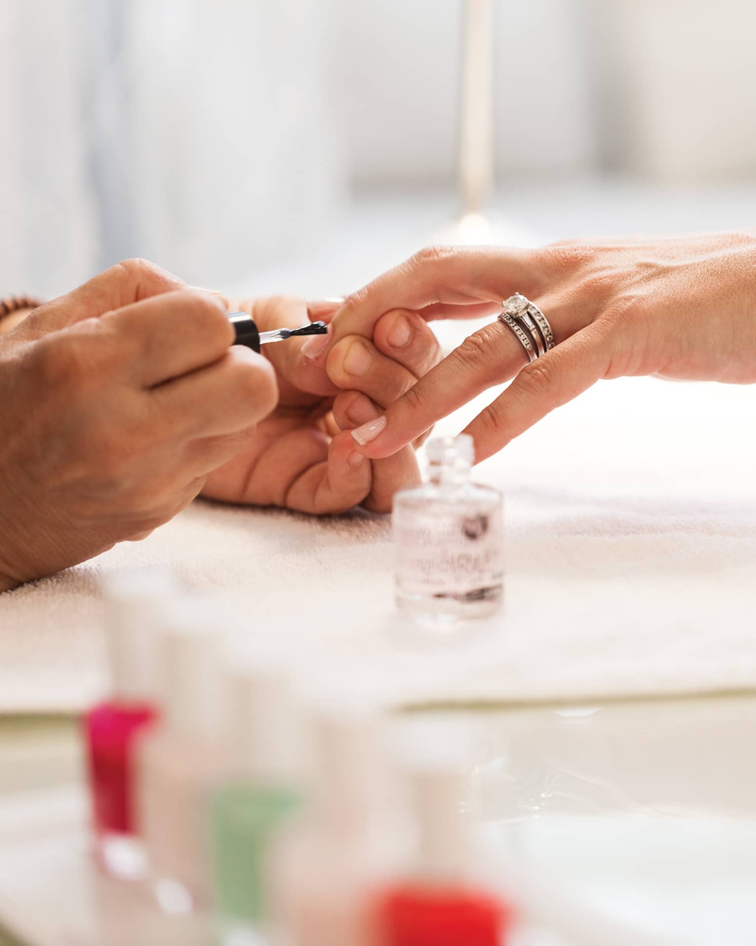 Close-up of woman in white robe getting clear polish manicure at spa table