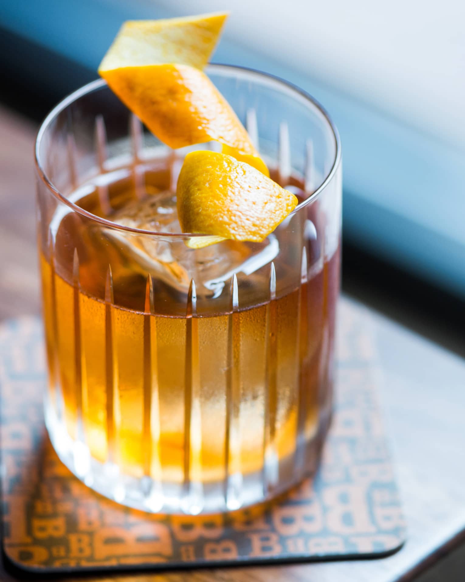 Rye whiskey cocktail in rock glass with ice cube, orange peel garnish