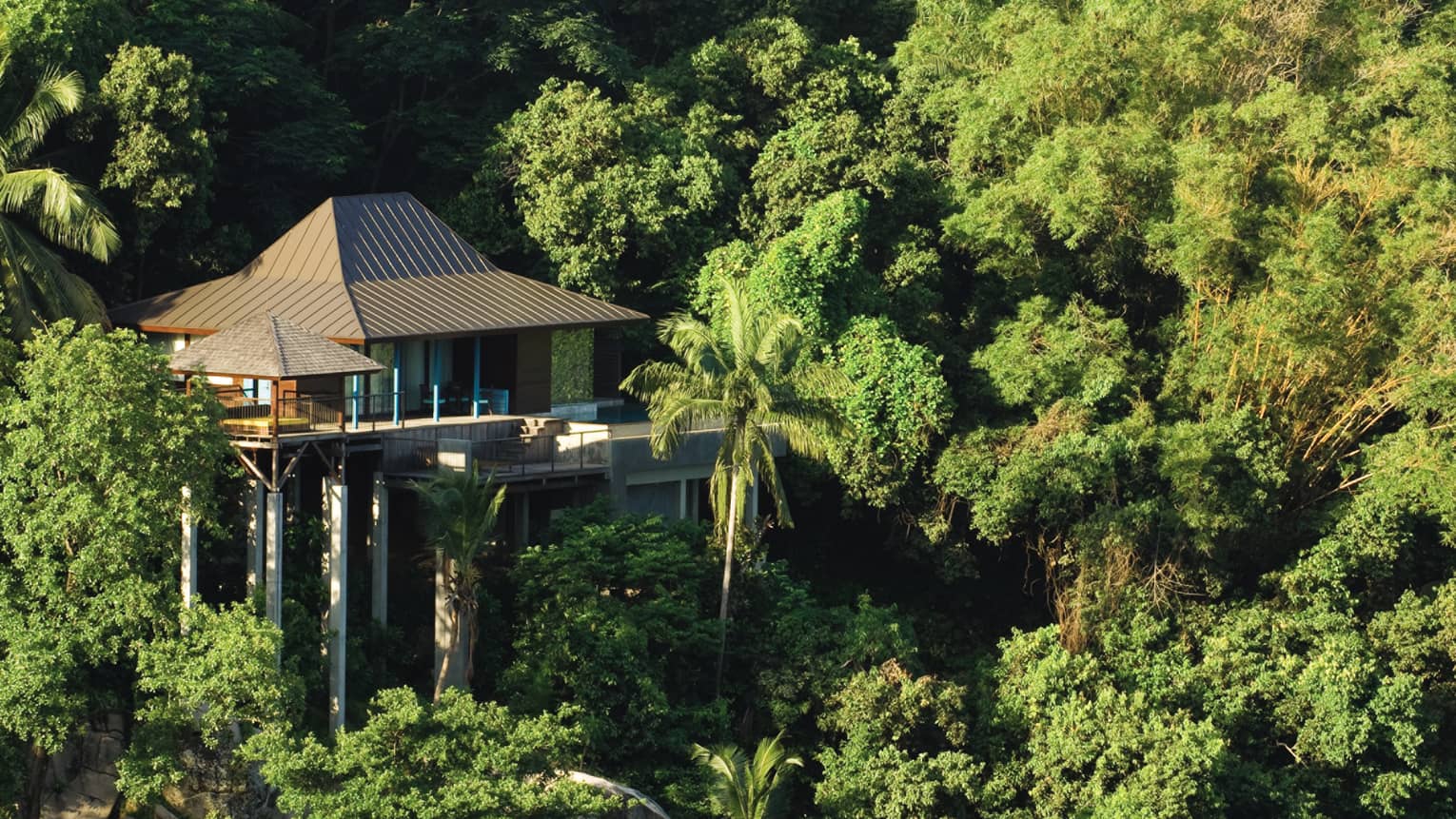 Looking down at Ocean-View Villa bungalow, rooftop on stilts high in lush green tropical mountain