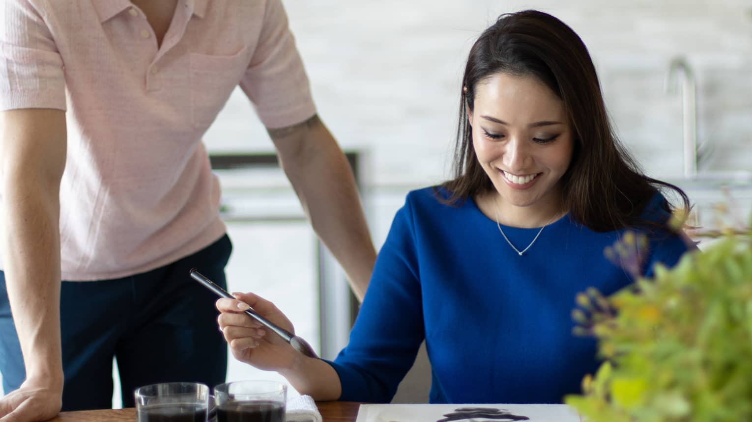 Person smiling while painting with watercolours at a table