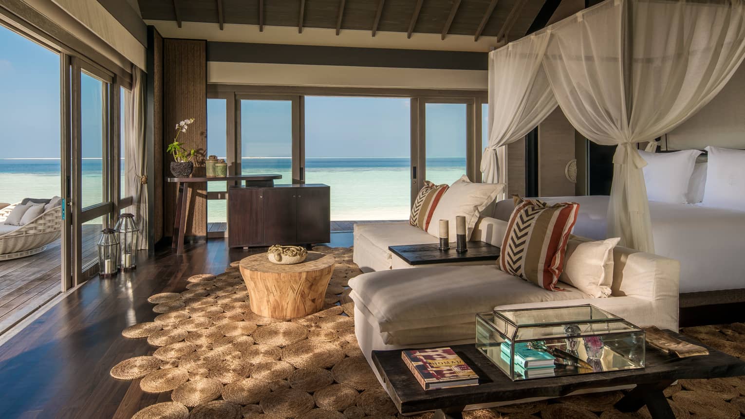 Three-Bedroom Beach Villa canopy bed. chaise lounge chairs across from open sliding doors to patio