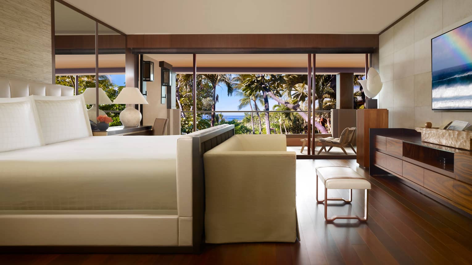 Ohana Partial Ocean-View Suite side view of bed with small white sofa, bench at foot, wood floors