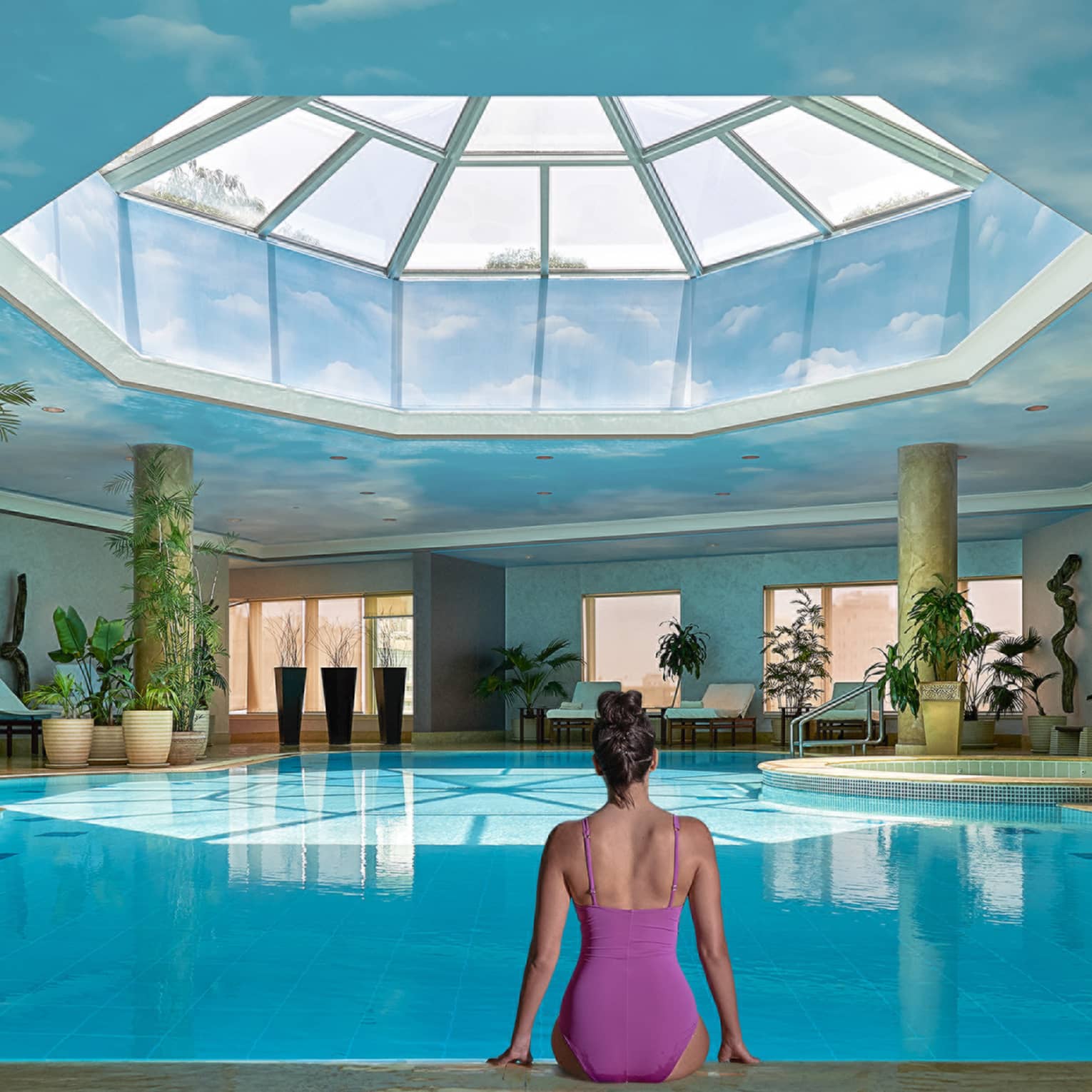 Woman in swimsuit seated on edge of indoor pool with blue ceiling and skylight above