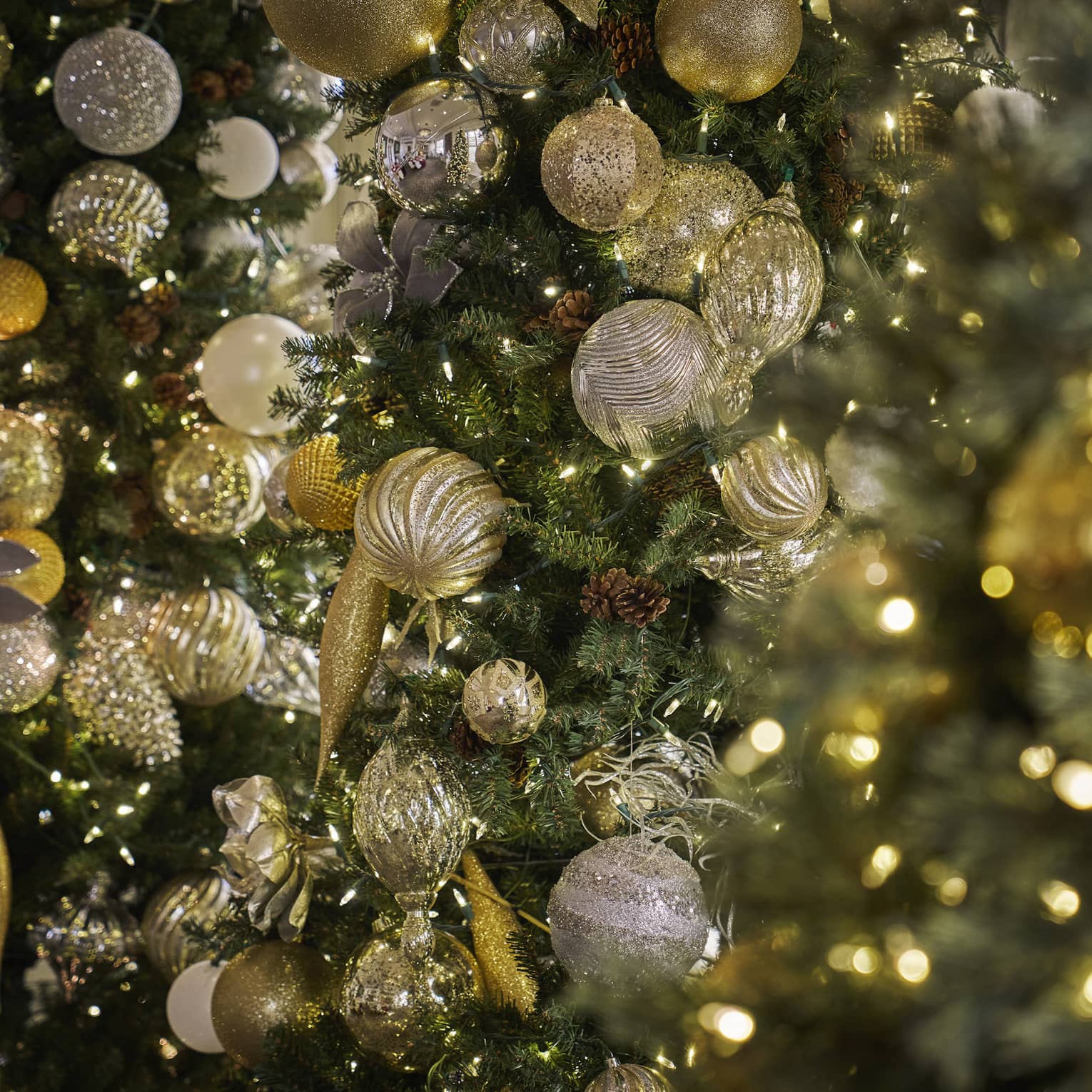 Closeup of Christmas tree with gold ornaments and white string lights