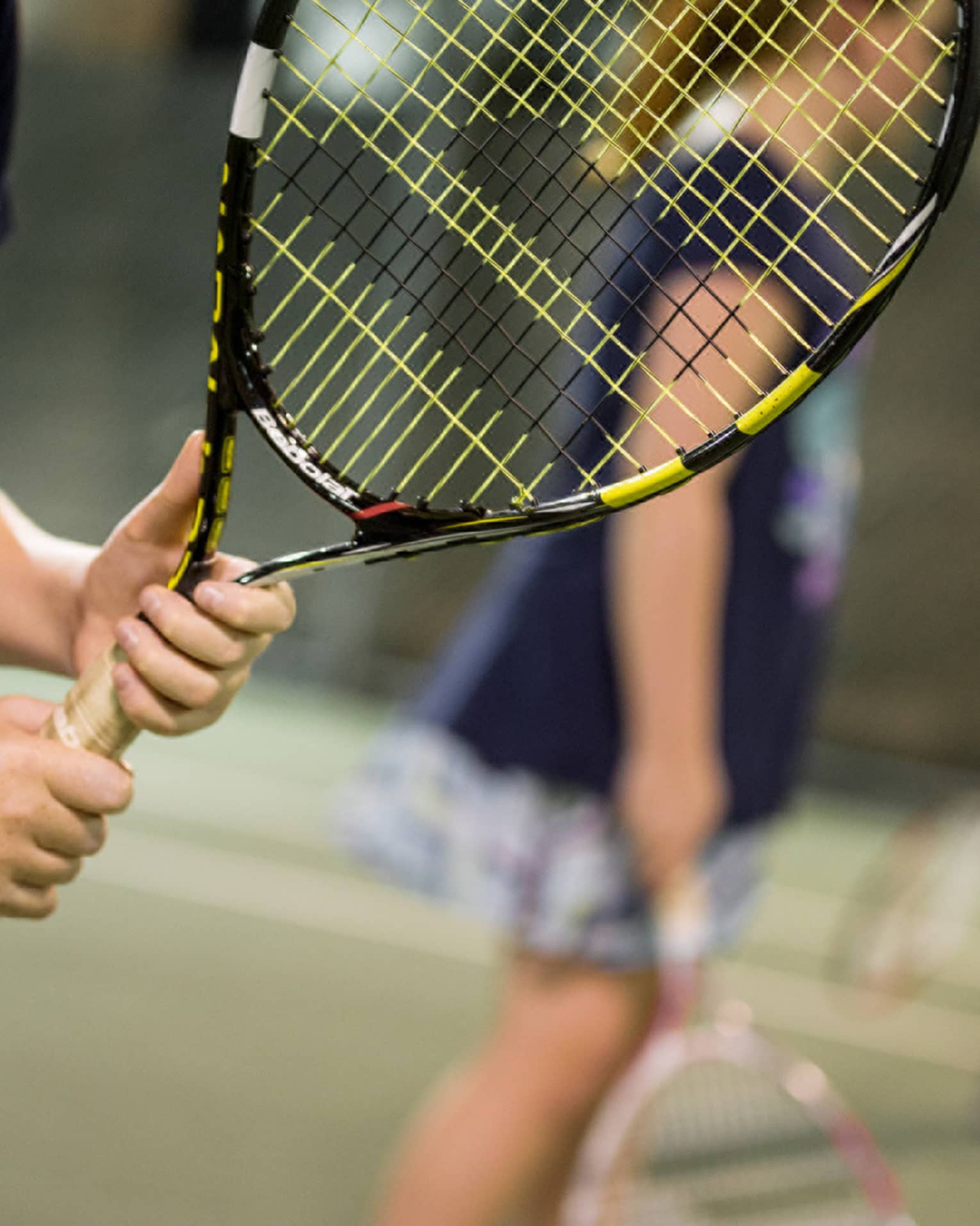 Close-up of hands holding yellow-and-black tennis racket