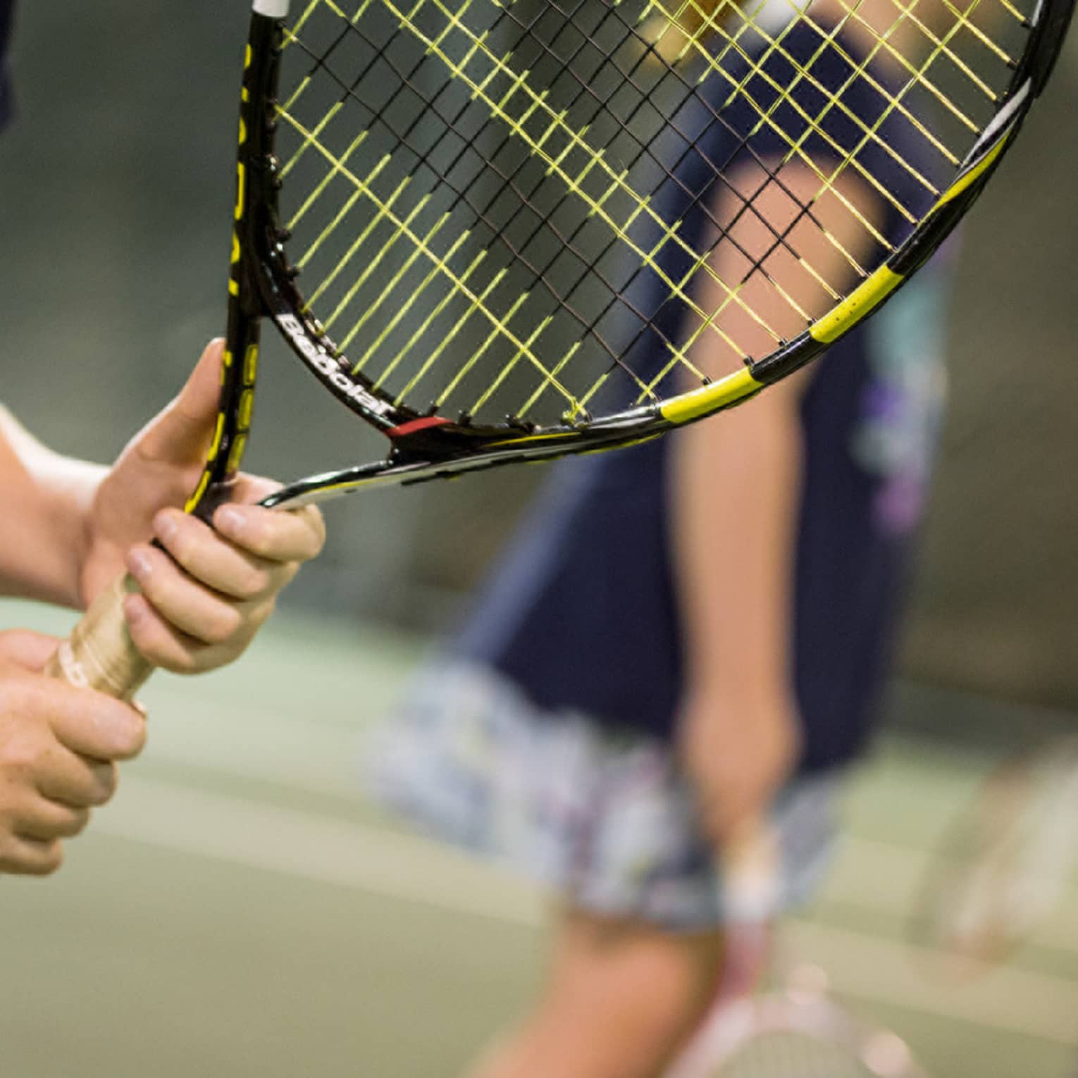 Close-up of hands holding yellow-and-black tennis racket