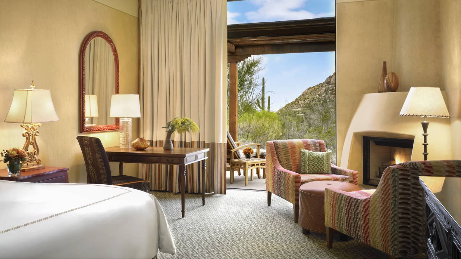 Premier Casita Room corner of bed, desk, armchairs by gas fireplace, mountain views through open balcony door