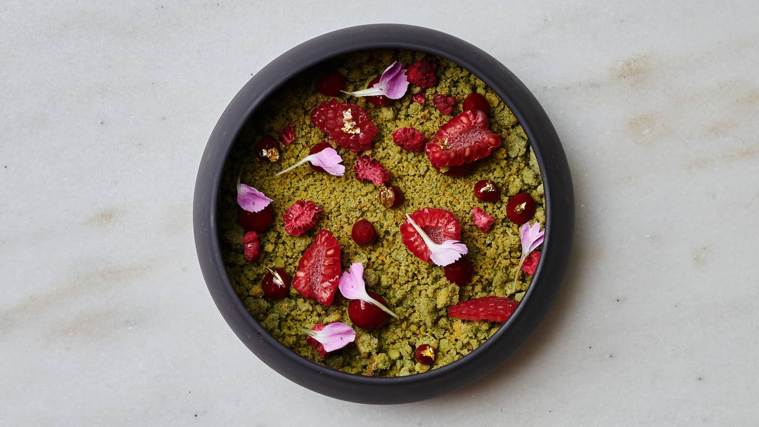 A dark round bowl containing colourful food items