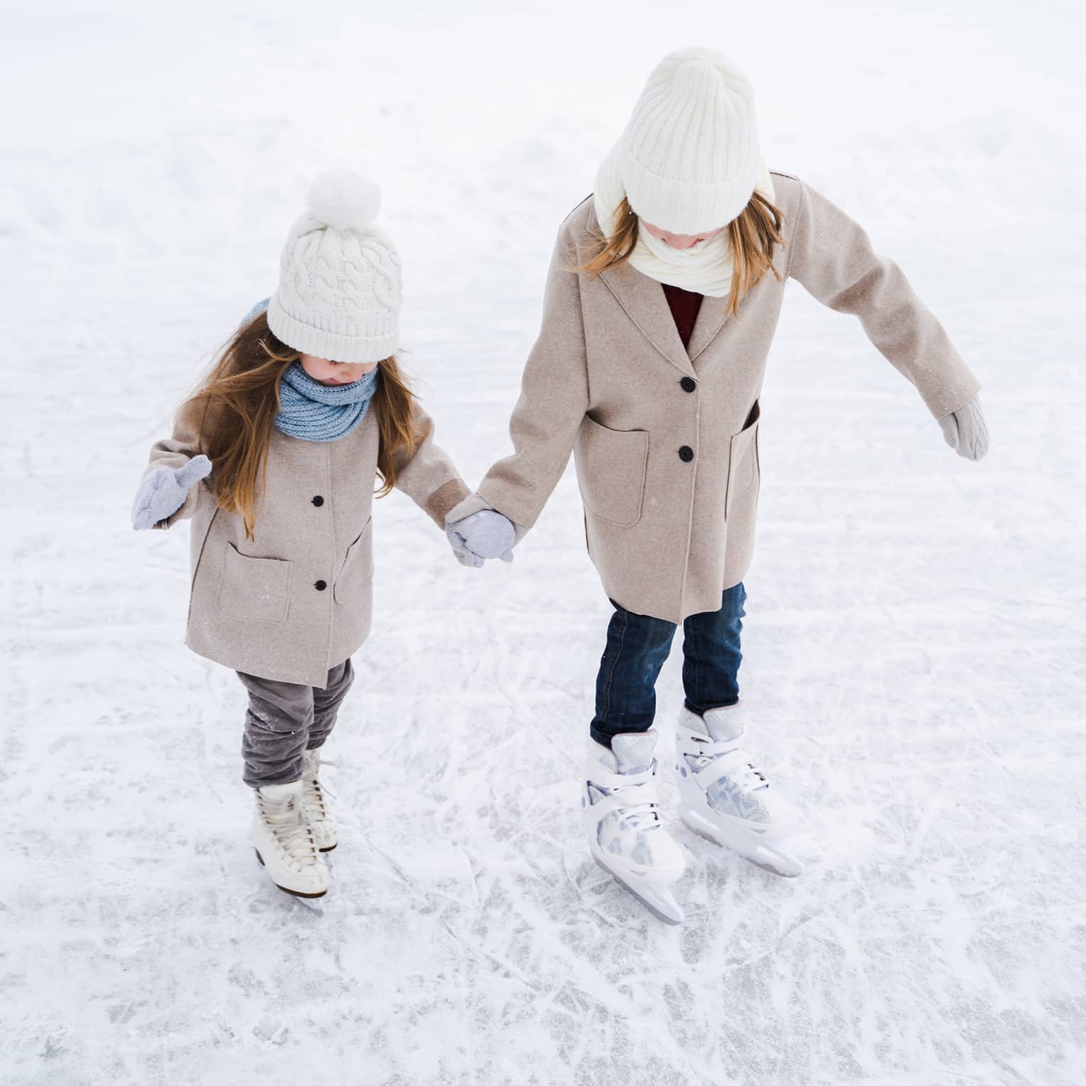 Two young girls ice skating.