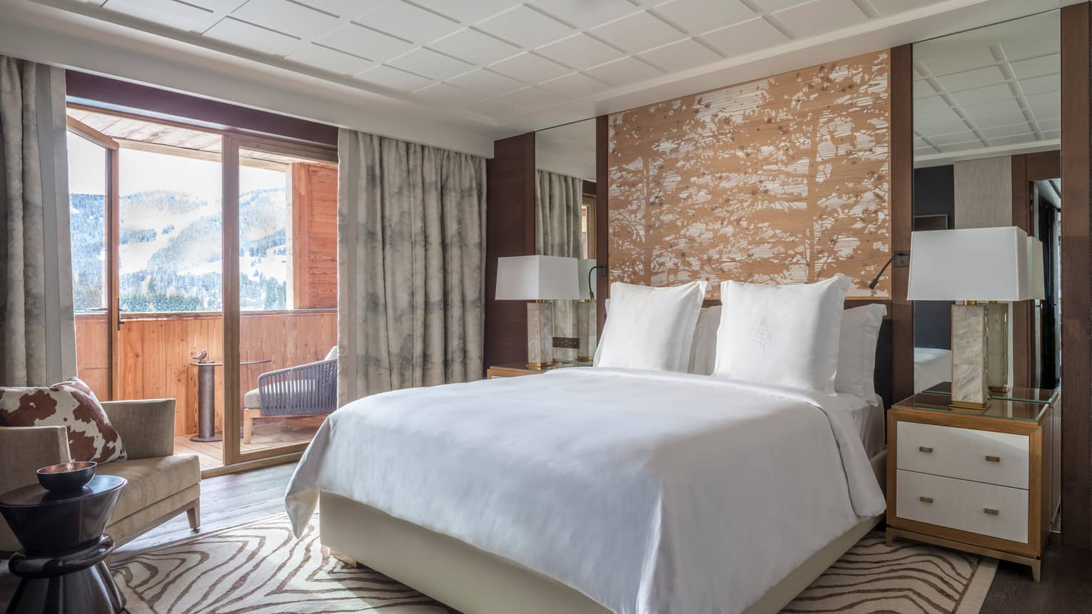 Deluxe Room bed, wood headboard with forest print, zebra print rug, armchair, cowhide pillow