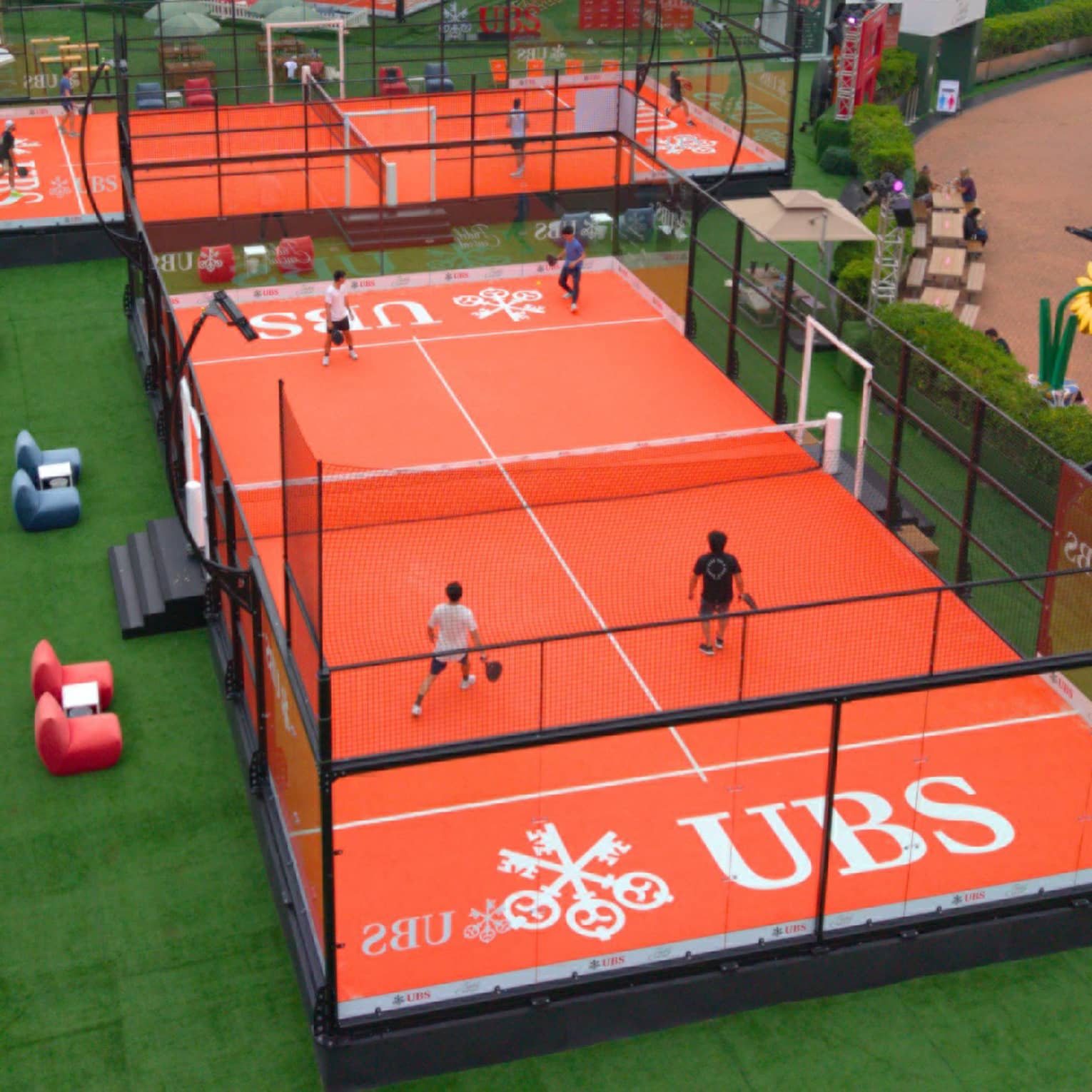 Red outdoor padel court with UBS logo on it