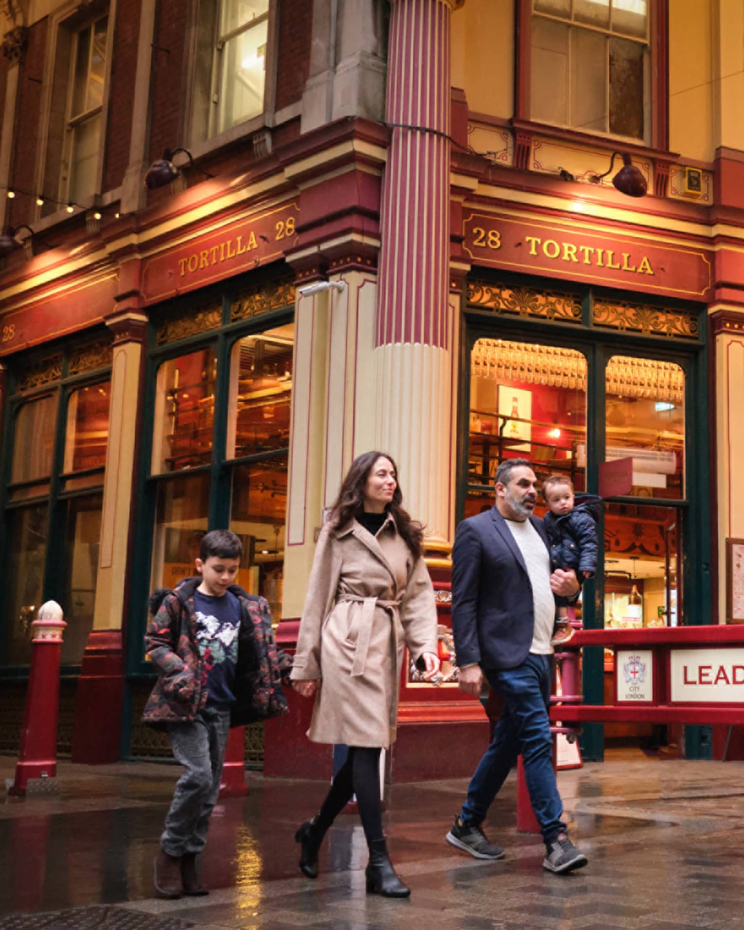 A family walks through London city street at night