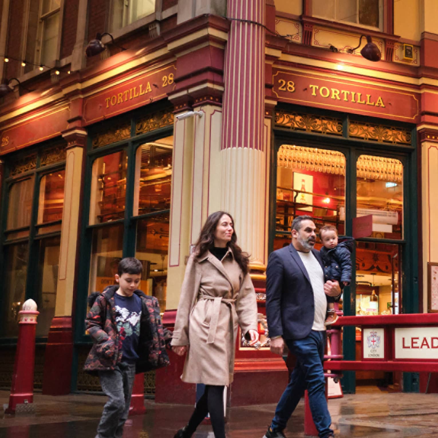 A family walks through London city street at night