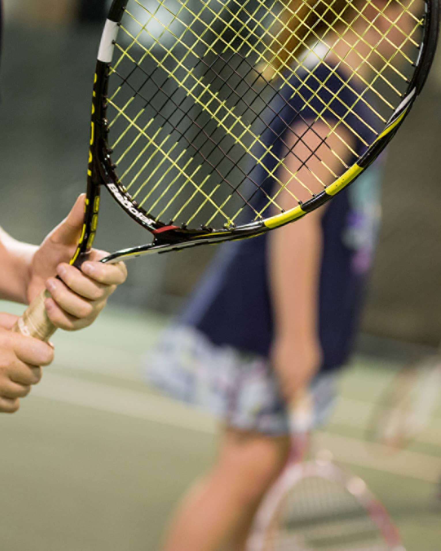 Close-up of hands holding yellow-and-black tennis racket